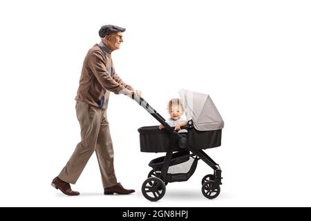 Ganzkörperaufnahme eines älteren Rentners, der auf weißem Hintergrund isoliert einen Kinderwagen schiebt und geht Stockfoto