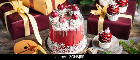 Große Weihnachten Neujahrs-Kuchen mit süßen Kugeln und Schneeflocken geschmückt, präsentiert Boxen Stapel auf rustikalem Hintergrund, Postkarte oder Einladungswagen Stockfoto