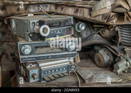 Stapel von alten Oldtimer-Radios und Kassettendeck schmutzig und kaputt beiseite geworfen mit anderen Junk aus einer vergangenen Ära Stockfoto