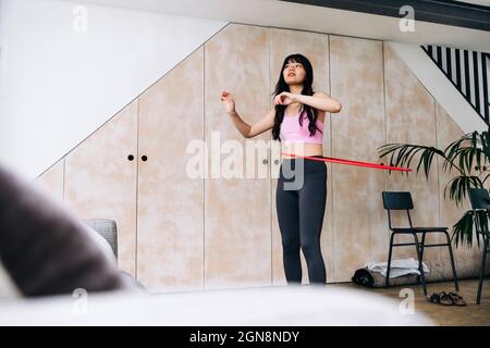 Junge Frau, die im Wohnzimmer einen Plastikreifen dreht Stockfoto