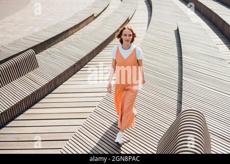 Junge Frau, die im Sommer auf Holzdielenbrett läuft Stockfoto