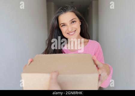 Schöne lächelnde Frau, die das Paket von der Lieferperson erhält Stockfoto