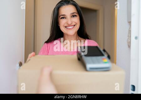 Lächelnde Frau, die das Paket von der Lieferperson erhält Stockfoto