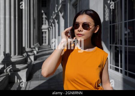 Frau mit Sonnenbrille beim Telefongespräch in der National Gallery Singapore, Singapur Stockfoto