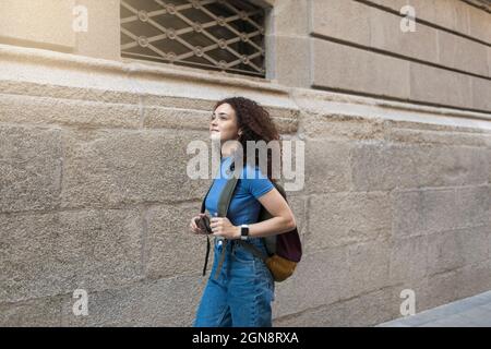 Junge Frau mit Rucksack an der Wand Stockfoto