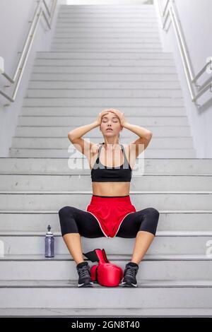 Boxerin mit Kopf in den Händen auf der Treppe sitzend Stockfoto