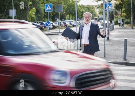 Schockiert männlichen professionellen Kreuzung durch rasenden Auto auf der Straße Stockfoto