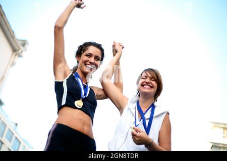 Glückliche weibliche Athleten mit Medaillen feiern den Erfolg Stockfoto