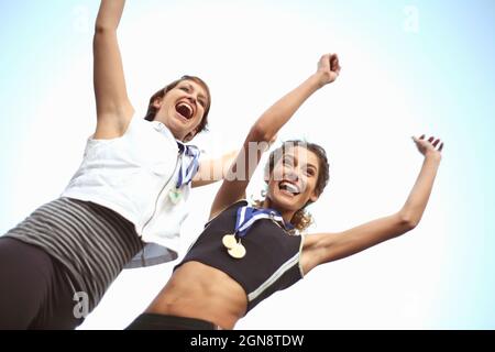 Glückliche weibliche Athleten mit Medaillen feiern den Erfolg Stockfoto