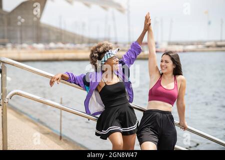 Glückliche Freundinnen, die sich an sonnigen Tagen High-Five geben Stockfoto