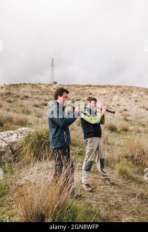 Männliche Freunde spielen Dulzaina, während sie auf dem Feld stehen Stockfoto