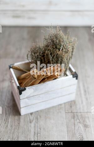 Zimtstangen und Rosmarin in weißem Holzbehälter Stockfoto