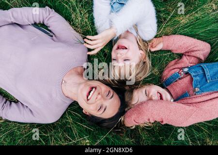 Fröhliche Mutter und Töchter liegen auf der Wiese Stockfoto