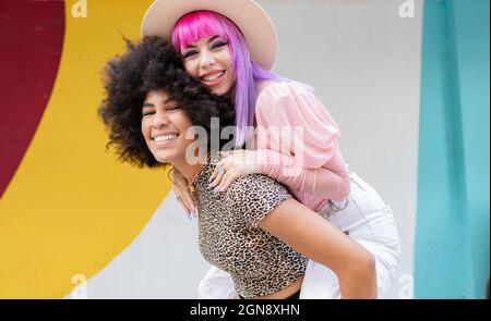 Junge Frau Huckepack Freundin vor der Wand Stockfoto