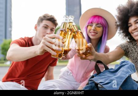 Multiethnische Freunde und Freundinnen, die Getränke im Park genießen Stockfoto