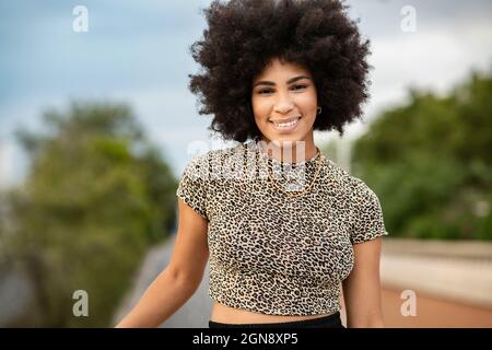 Lächelnde junge Afro-Frau im Oberteil mit Leopardendruck Stockfoto