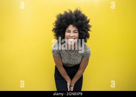 Afro-Frau lächelt vor der gelben Wand Stockfoto