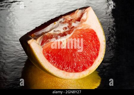 Geschnittene, verspiegelte gelbe Grapefruit auf schwarzem Hintergrund Stockfoto