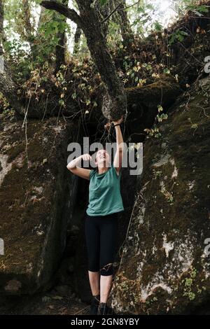 Lächelnde Frau mittleren Erwachsenen hält Zweig im Wald während des Wochenendes Stockfoto
