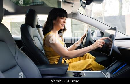 Glückliche Frau mit digitalen Tablet während der Fahrt Elektroauto Stockfoto