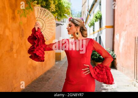 Tänzerin mit traditionellem Handfächer und Kleidung, die in der Gasse steht Stockfoto