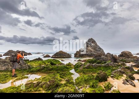 Männlicher Tourist, der vulkanische Felsen am Haywards Beach fotografiert Stockfoto