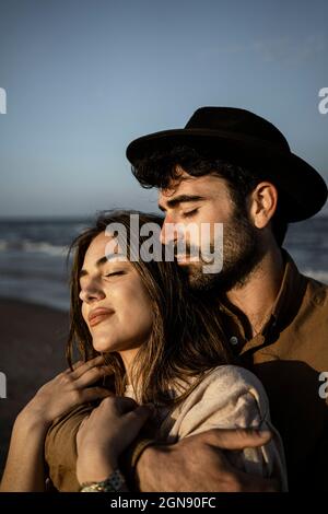 Mann umarmt Frau von hinten am Strand Stockfoto