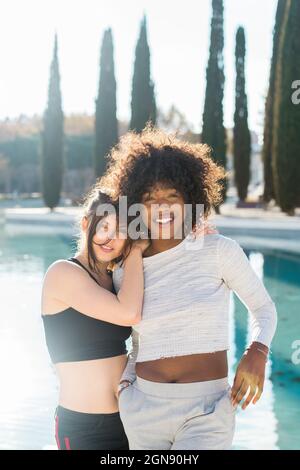 Lächelnde Freundin, die sich auf eine Frau im Park lehnt Stockfoto