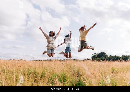 Glückliche Freunde genießen beim Springen auf der Wiese Stockfoto