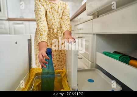 Mädchen wirft Plastikflasche in den Papierkorb zu Hause Stockfoto