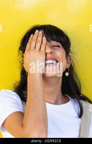Glückliche Frau, die das Auge mit der Hand bedeckt Stockfoto