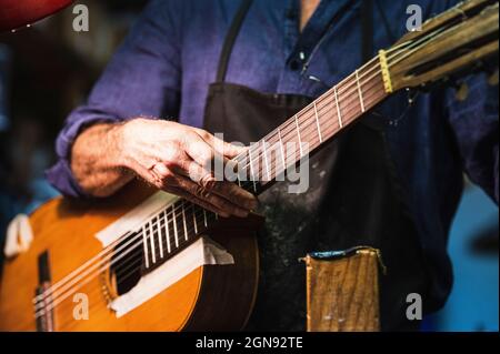 Geigenbauer prüft Gitarrensaiten in der Werkstatt Stockfoto