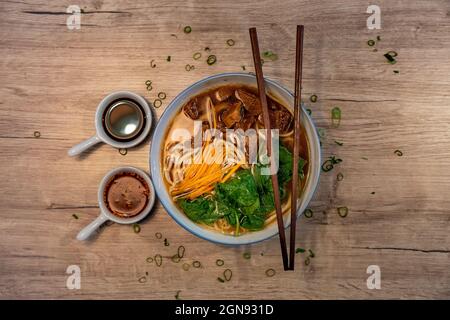 Rindernudelsuppe mit Gemüse, traditionelle chinesische Küche mit Soja- und Chilisauce auf der Seite Stockfoto