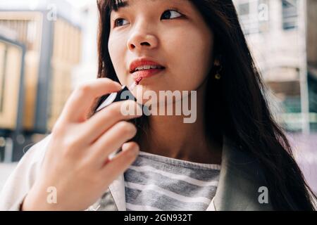 Junge Frau mit langen Haaren Anwendung Lipgloss Stockfoto