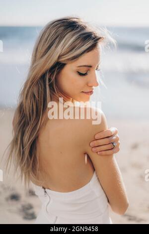 Schöne Braut im Hochzeitskleid am Strand stehen Stockfoto