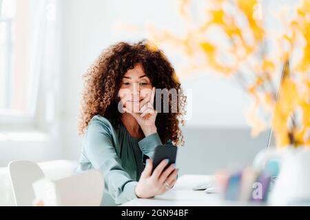 Seriöse Geschäftsfrau, die im Büro mit einem Laptop auf einem Stuhl sitzt Stockfoto