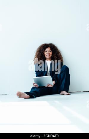 Professionelle Frau mit gekreuzten Armen und übergroßem Anzug vor der Wand Stockfoto