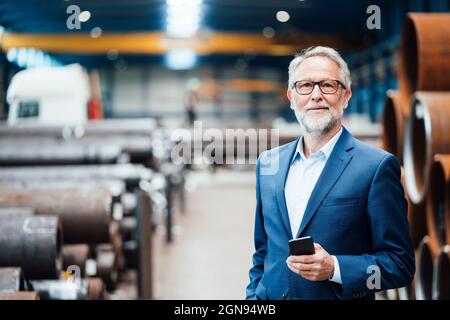 Männlicher Geschäftsführer, der in der Fabrik auf einem Sessel sitzt Stockfoto