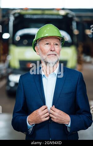 Lächelnder, männlicher Geschäftsführer, der im Lager mit Händen in den Taschen steht Stockfoto