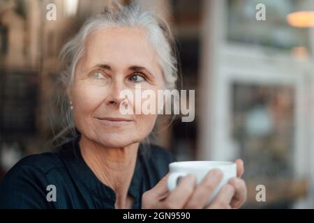 Lächelnde Frau hält Kaffeetasse im Café Stockfoto