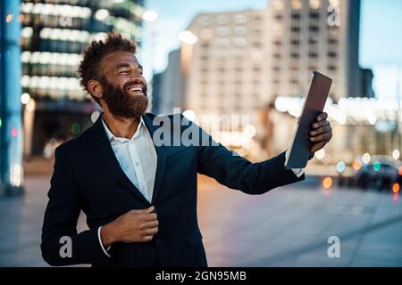 Glücklicher reifer Geschäftsmann nimmt Selfie durch digitale Tablet in der Stadt Stockfoto