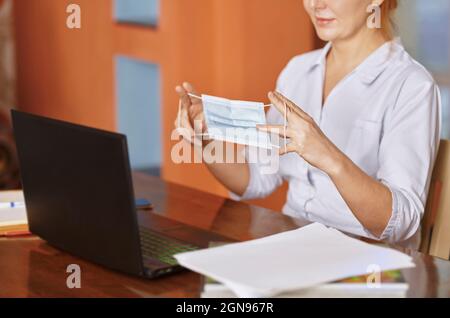 Krankenschwester hält eine schützende Gesichtsmaske während der Online-Konsultation Stockfoto