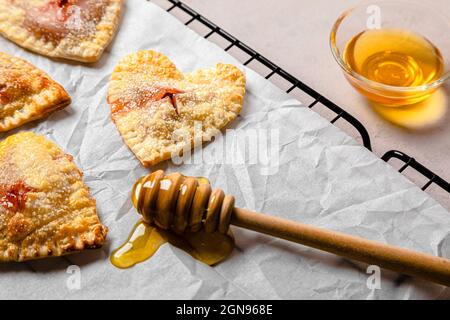 Studioaufnahme von herzförmigen Keksen und zwei Tassen Kaffee vor schwarzem Hintergrund Stockfoto