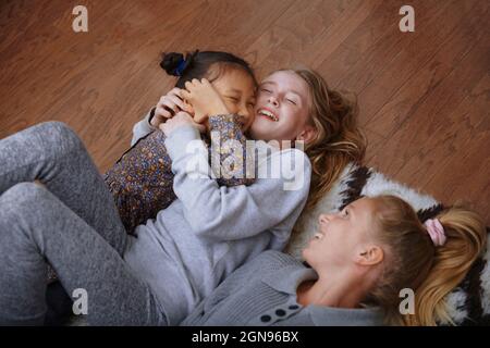 Glückliche Mädchen, die Spaß haben, während sie zu Hause auf dem Boden liegen Stockfoto