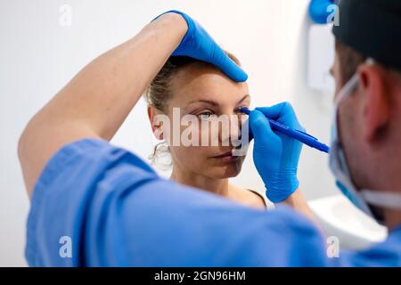 Chirurg zeichnet Linie auf Mädchen Auge mit Marker Vorbereitung für das Verfahren. Stockfoto