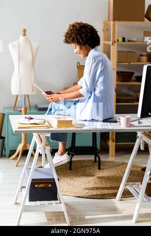 Selbstbewusste weibliche Modedesignerin mit gekreuzten Armen, die im Studio steht Stockfoto