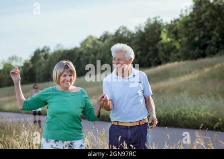 Fröhliches Seniorenpaar, das beim gemeinsamen Gehen die Hände hält Stockfoto