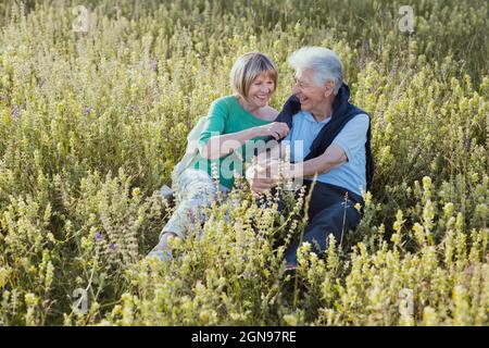 Fröhliches Seniorenpaar, das auf Gras sitzt Stockfoto