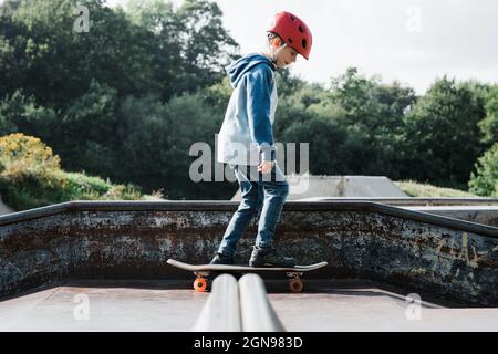 Boy Skateboarding mit Helm auf einem Skatepark in Großbritannien Stockfoto