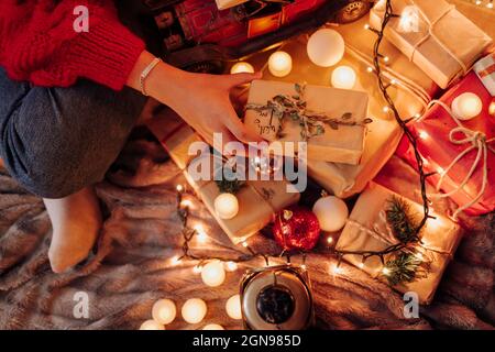 Junge Frau hält eingewickeltes Geschenk während der Weihnachtszeit zu Hause Stockfoto